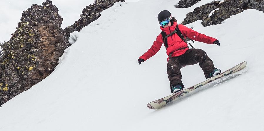 O snowboarder usa a borda do snowboard para cortar a neve enquanto faz uma curva
